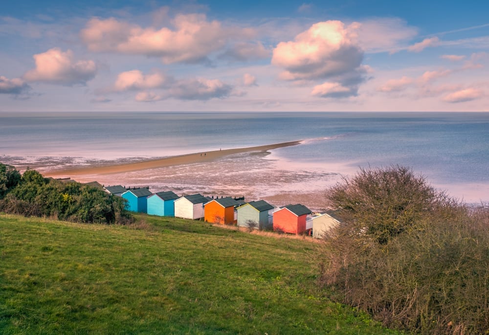 Impressive winter clouds in a cool blue sky over the Tankerton beach huts and natural spit of land that stretches out to sea