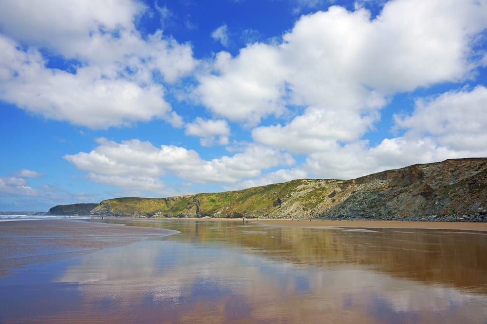 Reflections of blue sky and white clouds in the wet sands on the beach at Watergate bay near Newquay